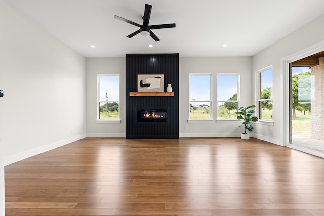 unfurnished living room with a healthy amount of sunlight, ceiling fan, hardwood / wood-style floors, and a fireplace