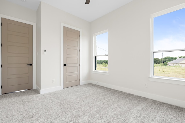 carpeted empty room featuring plenty of natural light and ceiling fan