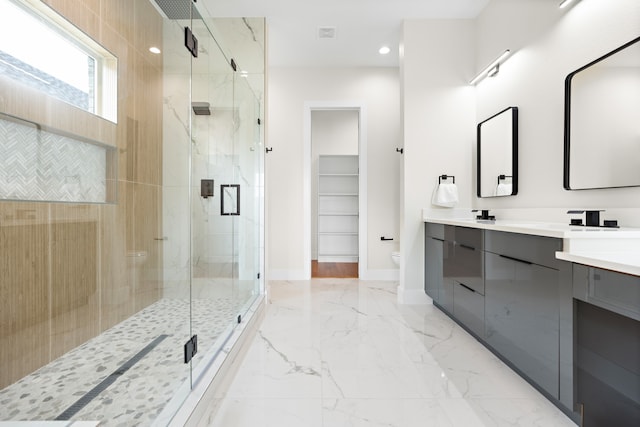 bathroom featuring a shower with door, vanity, and toilet