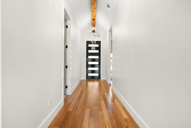 corridor with light hardwood / wood-style flooring and beam ceiling