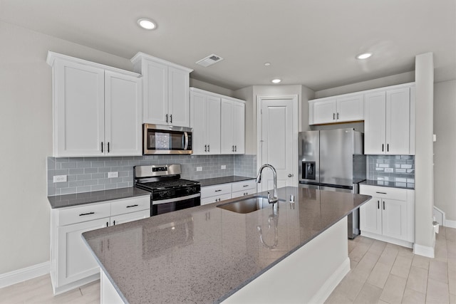 kitchen featuring appliances with stainless steel finishes, white cabinetry, sink, and a center island with sink