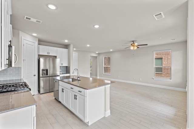 kitchen with white cabinetry, an island with sink, stainless steel appliances, and ceiling fan