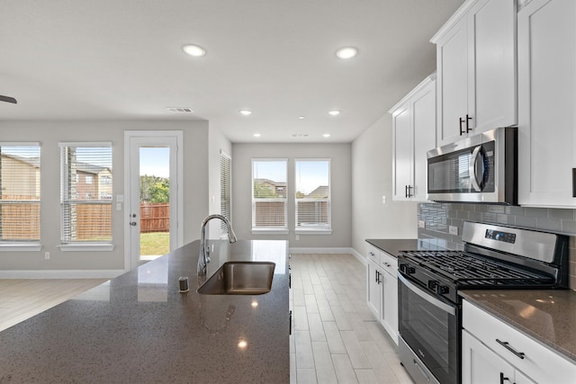 kitchen with a healthy amount of sunlight, sink, appliances with stainless steel finishes, and dark stone counters