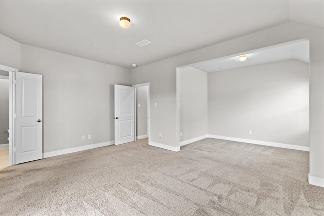 carpeted spare room with vaulted ceiling