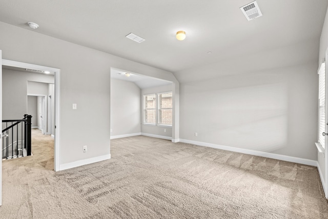 carpeted spare room with vaulted ceiling