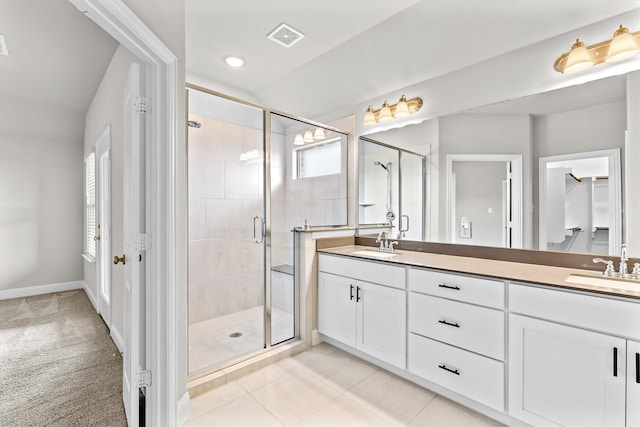 bathroom with a shower with door, vanity, a healthy amount of sunlight, and tile patterned floors