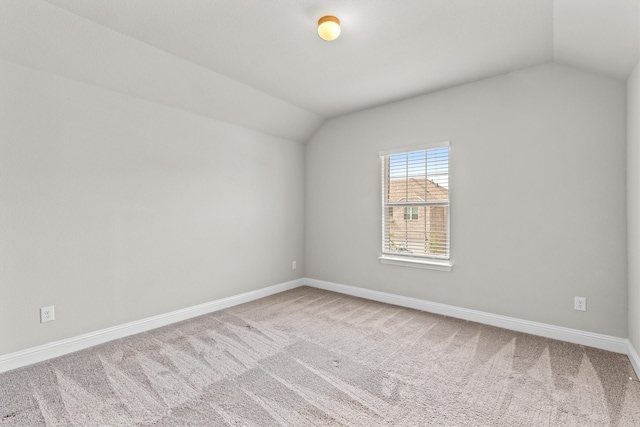 spare room featuring carpet flooring and vaulted ceiling