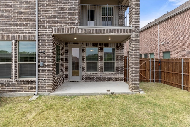 property entrance featuring a lawn and a patio