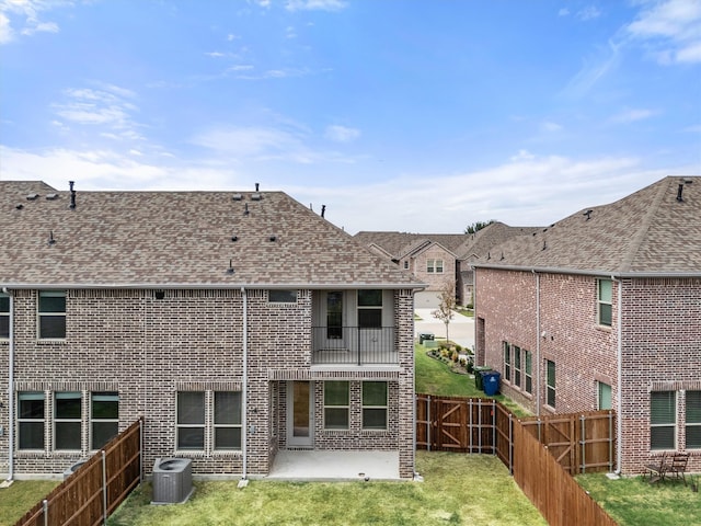 back of property featuring a balcony, a patio area, a yard, and cooling unit