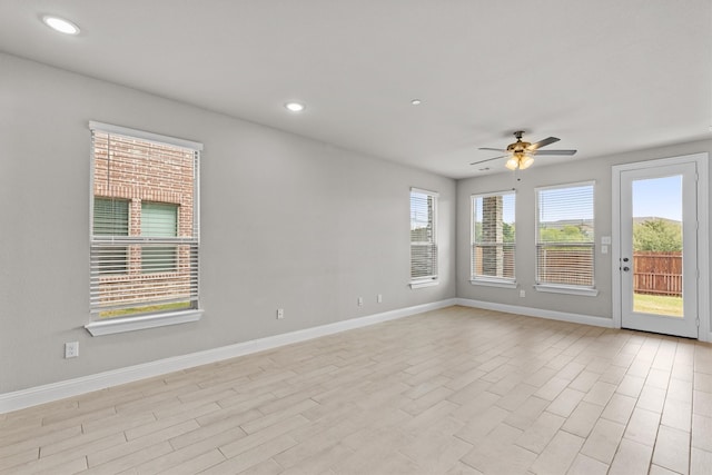 empty room featuring plenty of natural light, ceiling fan, and light hardwood / wood-style flooring