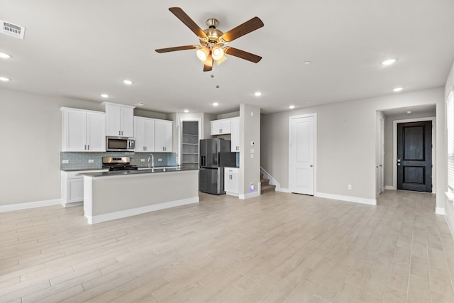 kitchen featuring light hardwood / wood-style flooring, appliances with stainless steel finishes, a kitchen island with sink, ceiling fan, and white cabinets