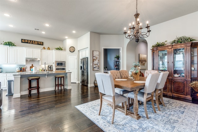 dining area with sink, dark hardwood / wood-style floors, and a chandelier