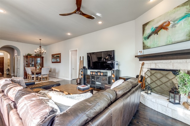 living room with dark wood-type flooring, a stone fireplace, and a chandelier