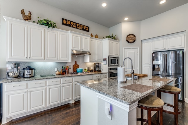 kitchen with dark hardwood / wood-style floors, an island with sink, stainless steel appliances, sink, and white cabinets