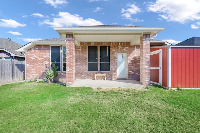 back of property featuring a patio area, a storage unit, and a lawn