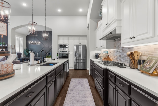 kitchen with decorative light fixtures, stainless steel appliances, sink, dark wood-type flooring, and white cabinets