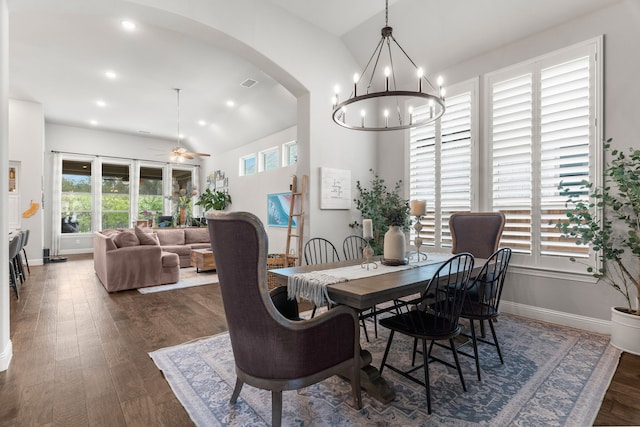 dining space with lofted ceiling, ceiling fan with notable chandelier, dark hardwood / wood-style floors, and a healthy amount of sunlight