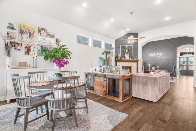 dining space with dark wood-type flooring, ceiling fan with notable chandelier, and high vaulted ceiling