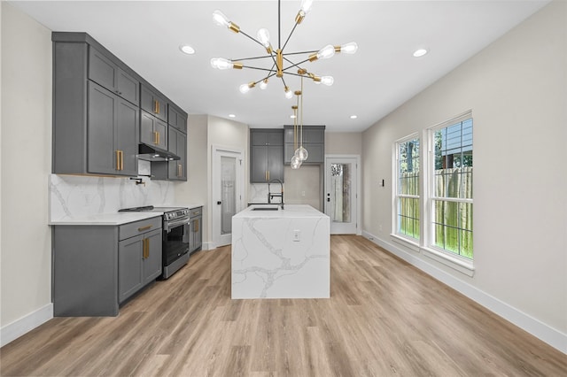 kitchen featuring a kitchen island with sink, wood-type flooring, decorative light fixtures, a chandelier, and stainless steel electric range oven