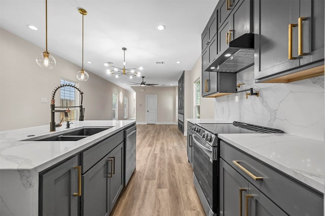 kitchen with light hardwood / wood-style floors, sink, light stone counters, stainless steel appliances, and hanging light fixtures