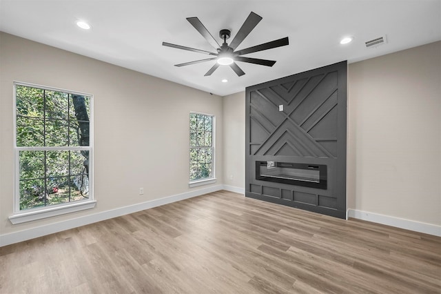 unfurnished living room featuring light hardwood / wood-style flooring, a wealth of natural light, and ceiling fan