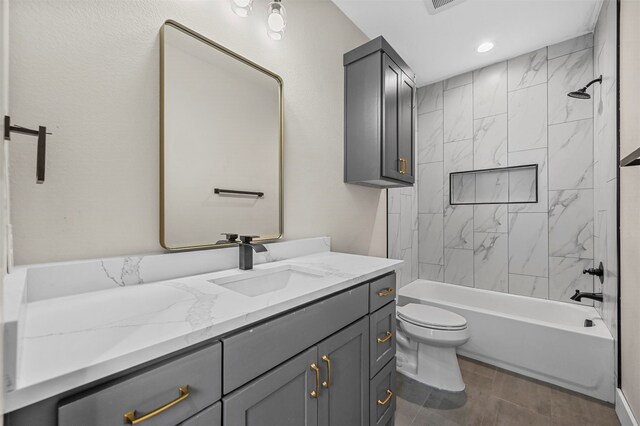 full bathroom featuring vanity, tiled shower / bath combo, and toilet