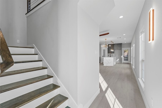 staircase with hardwood / wood-style floors and an inviting chandelier