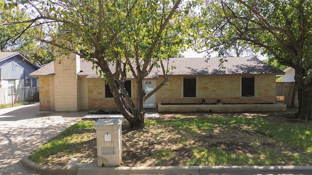 ranch-style house featuring roof with shingles and fence