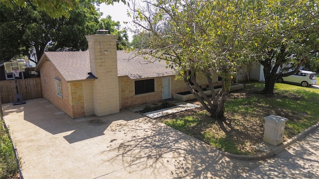 ranch-style home with a patio, fence, roof with shingles, concrete driveway, and a chimney