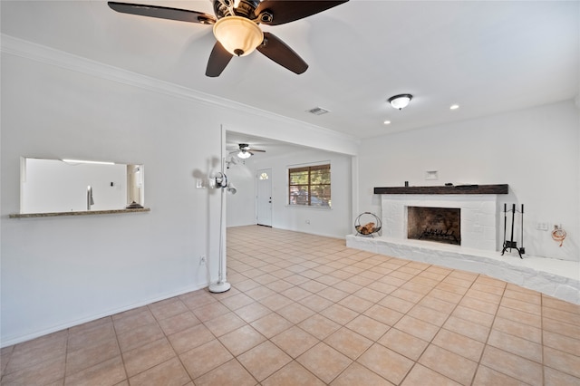 unfurnished living room with crown molding, a fireplace, ceiling fan, and light tile patterned floors