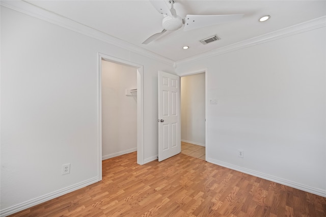 unfurnished bedroom with light hardwood / wood-style floors, a spacious closet, a closet, crown molding, and ceiling fan