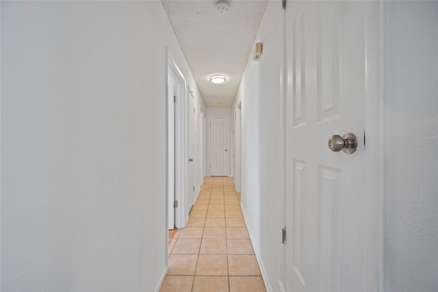 corridor with a textured ceiling and light tile patterned flooring