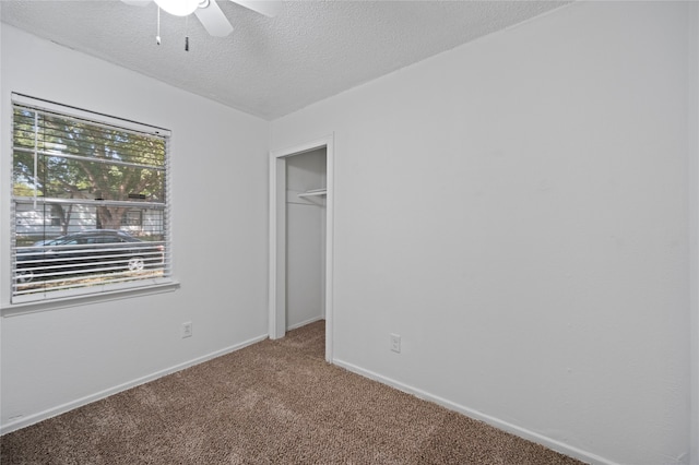 unfurnished bedroom featuring ceiling fan, a textured ceiling, a closet, and carpet flooring