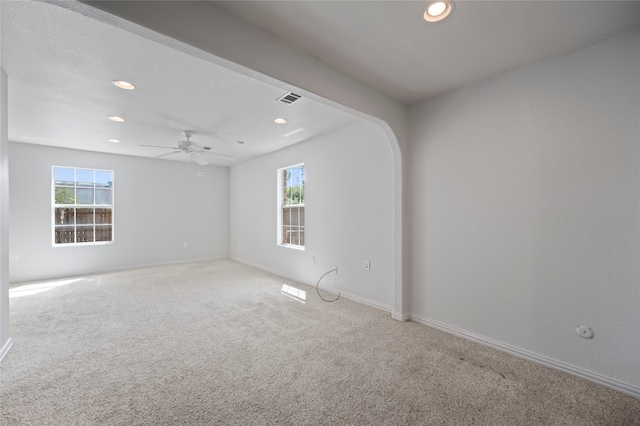 empty room with carpet floors, ceiling fan, and a wealth of natural light