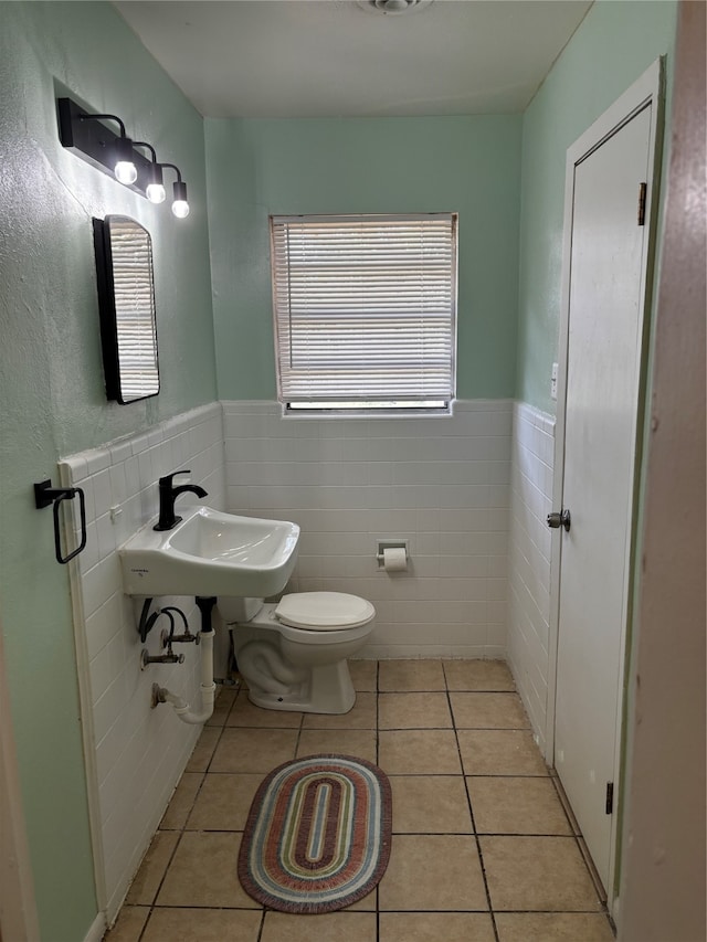 bathroom with tile walls, toilet, sink, and tile patterned flooring