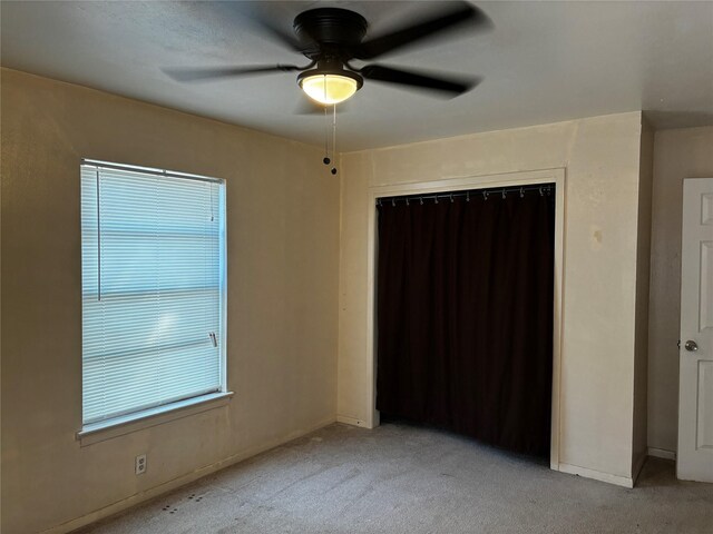 unfurnished bedroom with light colored carpet, ceiling fan, and a closet