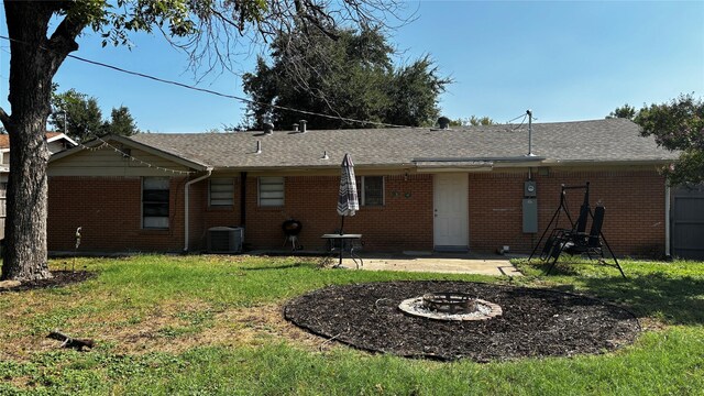 rear view of house with cooling unit, a lawn, a patio area, and an outdoor fire pit