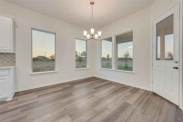 unfurnished dining area featuring light hardwood / wood-style floors and an inviting chandelier