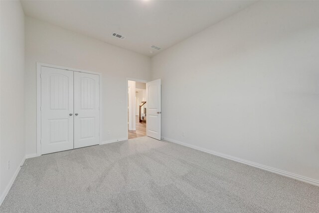 unfurnished bedroom featuring light carpet and a closet