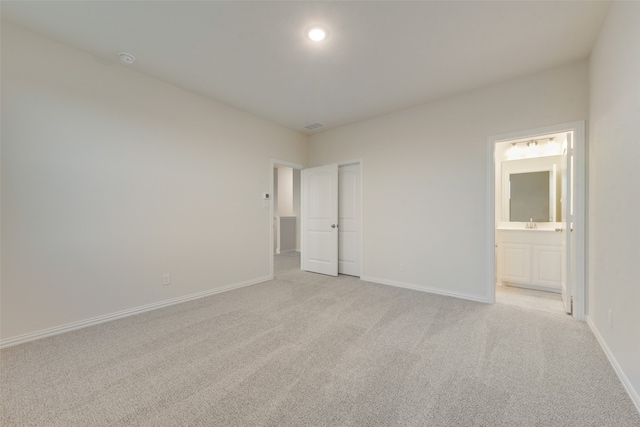 unfurnished bedroom featuring ensuite bath and light colored carpet