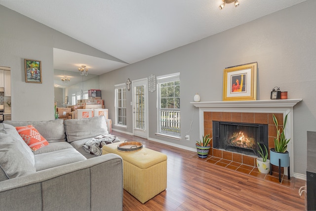 living room featuring a tile fireplace, lofted ceiling, and hardwood / wood-style flooring