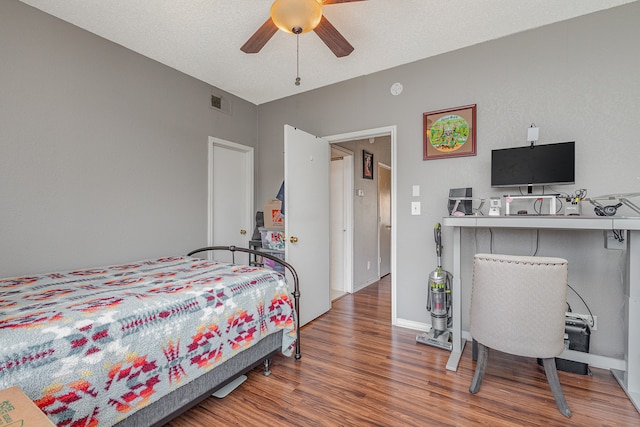 bedroom with a textured ceiling, dark hardwood / wood-style flooring, and ceiling fan