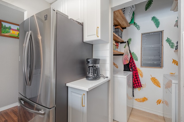 kitchen with white cabinets, stainless steel fridge, light wood-type flooring, and washer / dryer