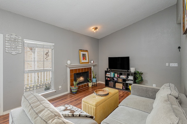 living room with a tile fireplace, wood-type flooring, and a textured ceiling