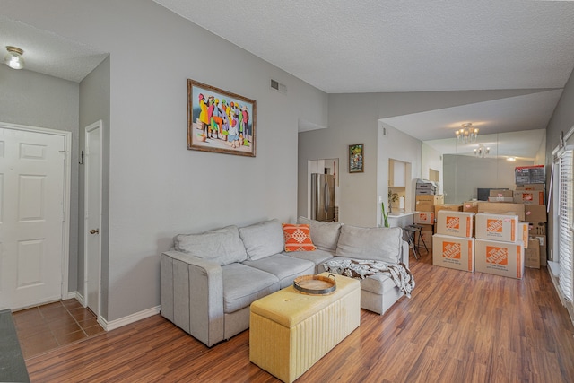 living room with a textured ceiling, wood-type flooring, and lofted ceiling