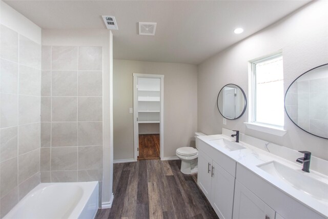 bathroom with a bath, hardwood / wood-style flooring, vanity, and toilet