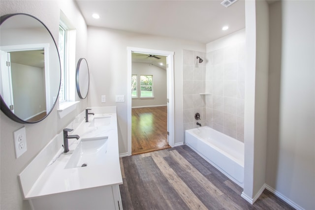 bathroom with hardwood / wood-style flooring, vaulted ceiling, ceiling fan, tiled shower / bath, and vanity