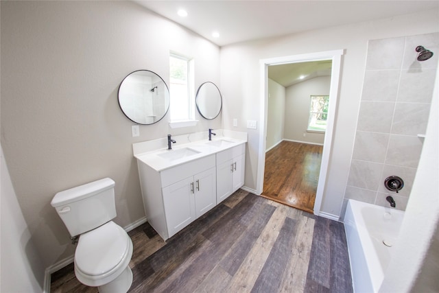 full bathroom featuring vanity, lofted ceiling, hardwood / wood-style flooring, toilet, and tiled shower / bath