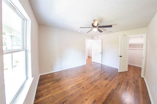 unfurnished bedroom featuring ceiling fan, dark wood-type flooring, and a spacious closet