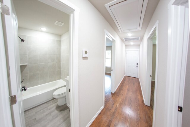 bathroom featuring hardwood / wood-style floors, tiled shower / bath, and toilet